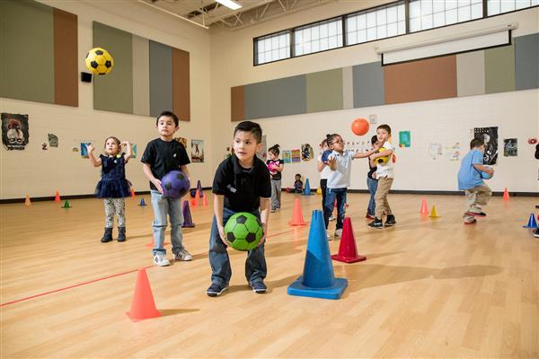 Students play with soccer balls in a gym. 